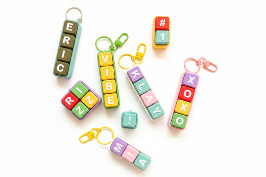 Colorful keychains with letter and number designs on a green grid background